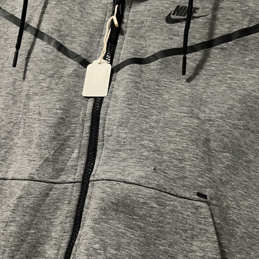 Nike Tech Fleece Full-Zip Hoodie Grey (Category: Hoodies) located in Argao. Submitted by secondcyclecollection (Listing ID 1465962431, Image 3). Description: - Brand: Nike - Style: Tech Fleece Full-Zip Hoodie - Color: Grey with black contrast taped pockets and zip lines - Size: Large (Standard fit) - Design: Classic chevron across the chest - Features: Built-in hood with adjustable black drawstrings, two zipped side pockets - Condition/Origin: Ma