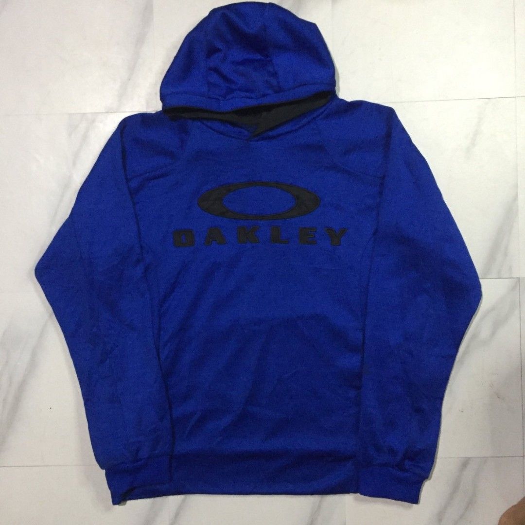 Oakley Blue Pullover Hoodie XXL (Category: Coats, Jackets and Outerwear) located in Imus. Submitted by thrifts_select (Listing ID 1465996123, Image 1). Description: - Brand: Oakley - Size: XXL - Color: Bright blue with a large black logo on the chest - Material: 100% polyester fabric - Features: Double-layered hood with black inner lining, ribbed cuffs, and hem - Condition: Good as tag shows branding and manufacturing details 24x30 no lace and ne