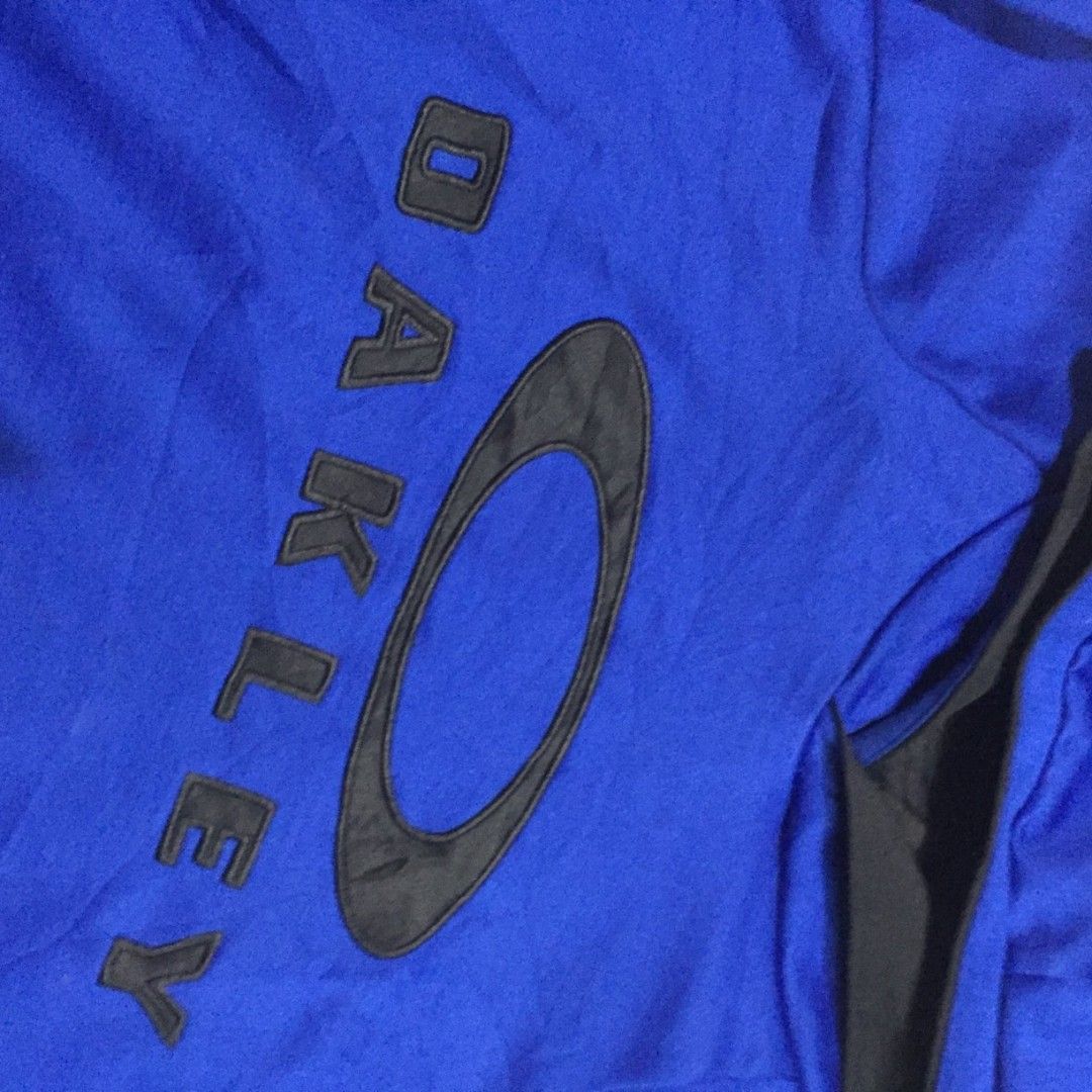Oakley Blue Pullover Hoodie XXL (Category: Coats, Jackets and Outerwear) located in Imus. Submitted by thrifts_select (Listing ID 1465996123, Image 2). Description: - Brand: Oakley - Size: XXL - Color: Bright blue with a large black logo on the chest - Material: 100% polyester fabric - Features: Double-layered hood with black inner lining, ribbed cuffs, and hem - Condition: Good as tag shows branding and manufacturing details 24x30 no lace and ne