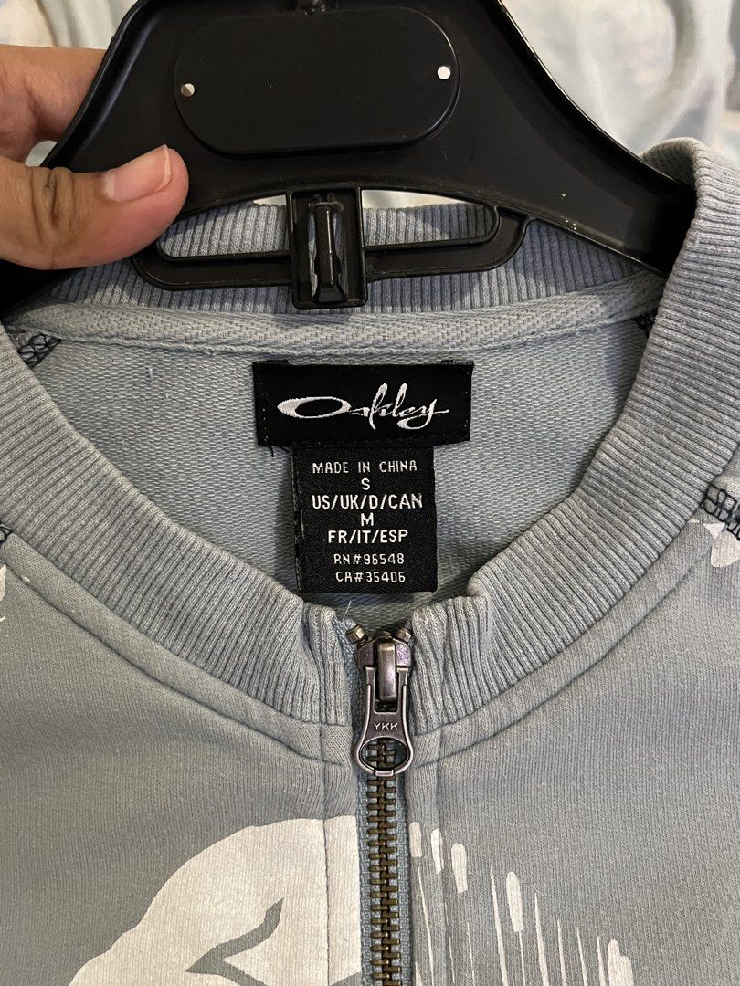 Oakley Fall 2009 Graphic Zip-Up Jacket (Category: Coats, Jackets and Outerwear) located in Paranaque City. Submitted by alasthrift26 (Listing ID 1465966760, Image 3). Description: - Brand/Era: Authentic Oakley Fall 2009 collection - Size: Small (S) - Color & Design: Light blue with a bold abstract graphic print across the front - Details: Front pouch pockets, embroidered Oakley script, ribbed collar, cuffs, and hem - Hardware: Premium YKK zipper 