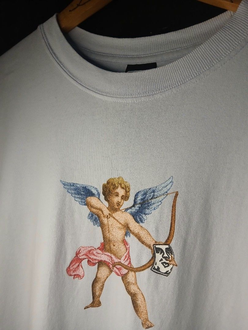 Obey (Category: Tshirts & Polo Shirts ) located in Caloocan City. Submitted by benthriftshp (Listing ID 1466122978, Image 3). Description: - Color: Light blue - Design: Detailed cupid graphic print on the front - Fit: Relaxed fit with classic crew neck and short sleeves - Material: Soft, lightweight, and comfortable for daily wear - Condition: Excellent, 680.