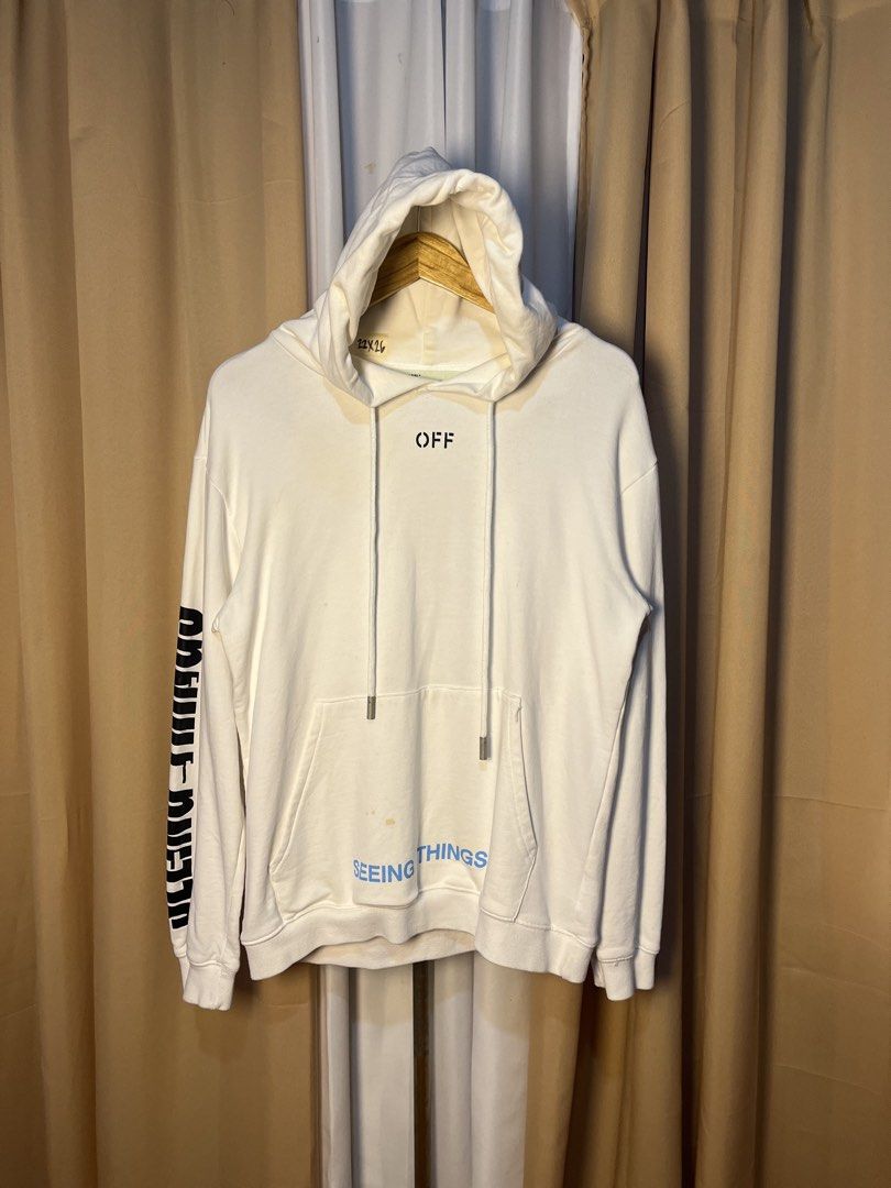 Off-White Seeing Things White Hoodie (Category: Hoodies) located in Kidapawan. Submitted by azythrift (Listing ID 1466050156, Image 1). Description: - Brand: Off-White - Color: White - Design: 'OFF' text on chest, 'SEEING THINGS' print on sleeve and near pocket - Details: Long drawstrings with metal aglets - Size: 22x26 (Measurements on hanger tag) - Condition: Flawed - yellowish staining visible around collar, chest, and bottom pocket area - PM 