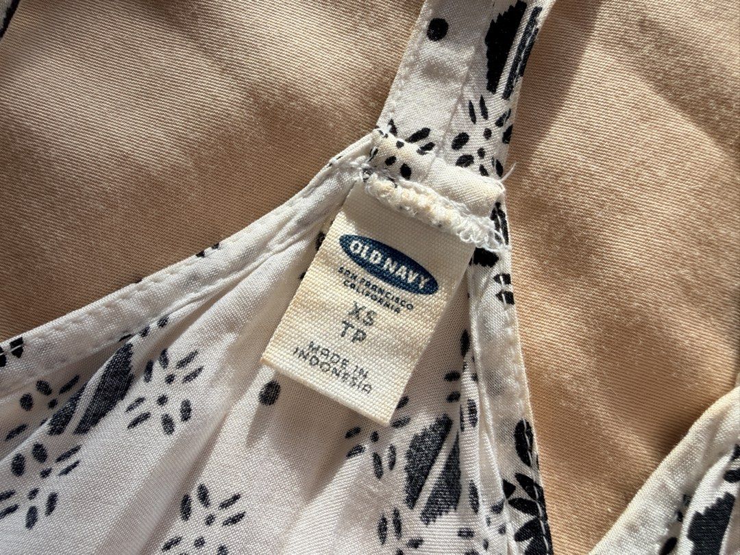 Old Navy Black and White Patterned Halter Tank Top (Category: Sleeveless) located in Quezon City. Submitted by makingroomfinds (Listing ID 1466066233, Image 2). Description: - Brand: Old Navy - Size: XS - Design: Black and white geometric pattern with a detailed border hem - Straps: Adjustable spaghetti straps with a stylish racerback - Fabric: Lightweight and breathable, ideal for sunny days or layering - Flaw: Minor discoloration near the colla