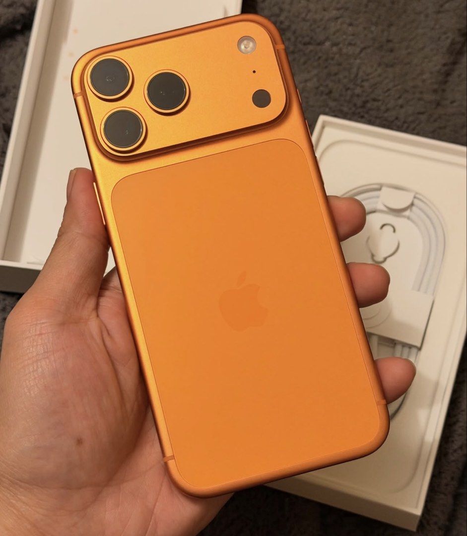Orange Apple iPhone (Category: iPhone 17 Series) located in Manila. Submitted by trustedseller1902 (Listing ID 1465999636, Image 2). Description: - Model/Color: Bright orange body with matching camera bump and iconic Apple logo - Camera: Advanced triple-lens setup - Design: Modern flat edges with responsive volume and power buttons - Inclusions: Comes with the original box, charging cable, and SIM ejector tool - Condition: Excellent, ready for a 