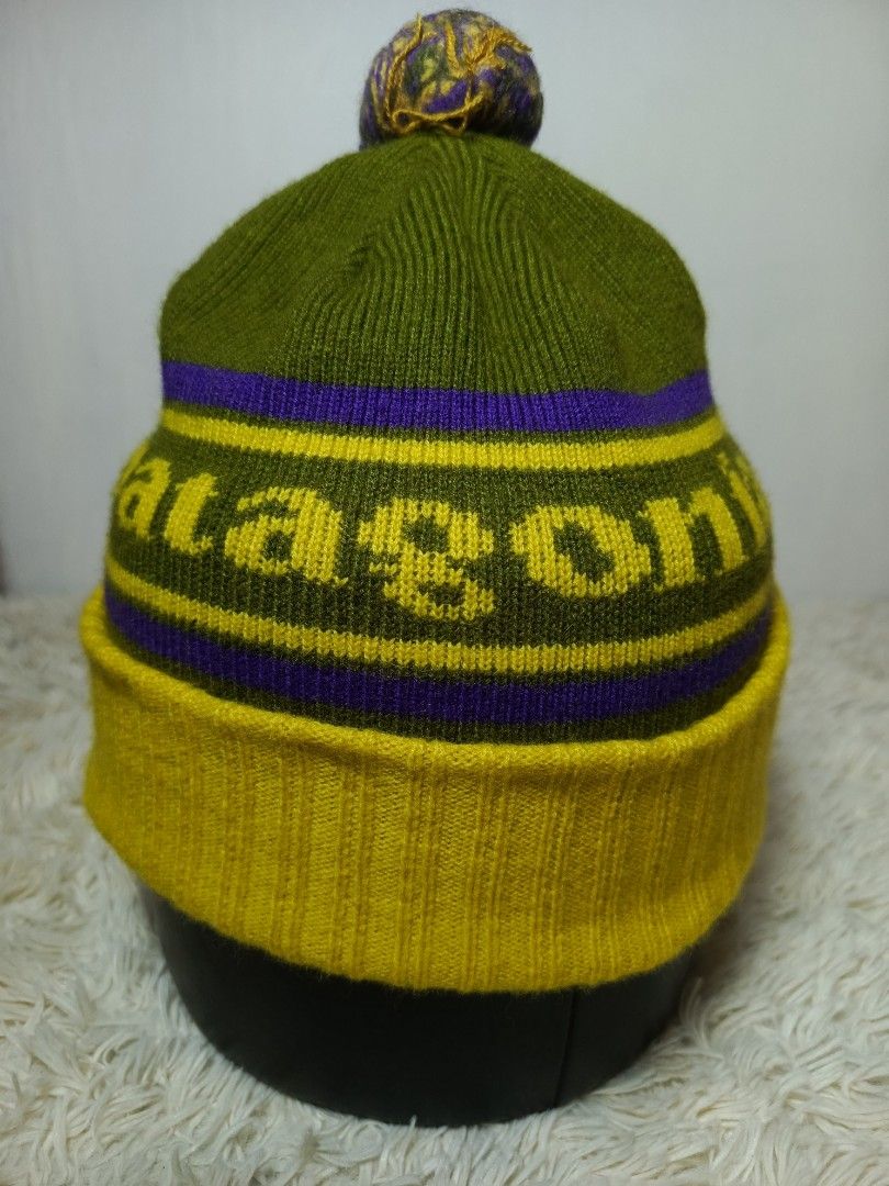 PATAGONIA POM POM BENNIE (Category: Caps & Hats) located in Baguio. Submitted by 074thriftmania (Listing ID 1466116376, Image 2). Description: - Brand: Patagonia - Style: Winter beanie with pom pom - Colorway: Olive green body with yellow/purple stripes and text - Details: Thick ribbed yellow fold-over cuff with front black logo label - Material: Warm, high-quality knit for cold weather - Condition: Brand new / Excellent (ready to ship) OSFA .