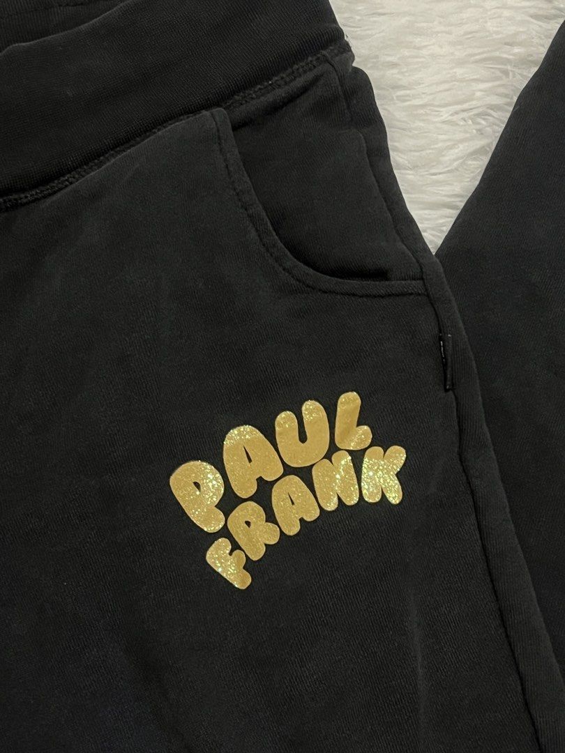 Paul Frank Black Gold Glitter Sweatpants (Category: Joggers) located in Tuguegarao City. Submitted by love_clothies (Listing ID 1465968570, Image 3). Description: - Brand: Paul Frank - Color: Black with shiny gold glitter logo on the left leg - Material: Soft, comfortable cotton - Features: Elastic waistband, black drawstring, side pockets, and ribbed ankle cuffs - Condition: In solid shape overall - Best for: Lounging at home or casual daily err