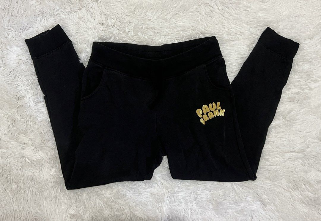 Paul Frank Black Gold Glitter Sweatpants (Category: Joggers) located in Tuguegarao City. Submitted by love_clothies (Listing ID 1465968570, Image 1). Description: - Brand: Paul Frank - Color: Black with shiny gold glitter logo on the left leg - Material: Soft, comfortable cotton - Features: Elastic waistband, black drawstring, side pockets, and ribbed ankle cuffs - Condition: In solid shape overall - Best for: Lounging at home or casual daily err
