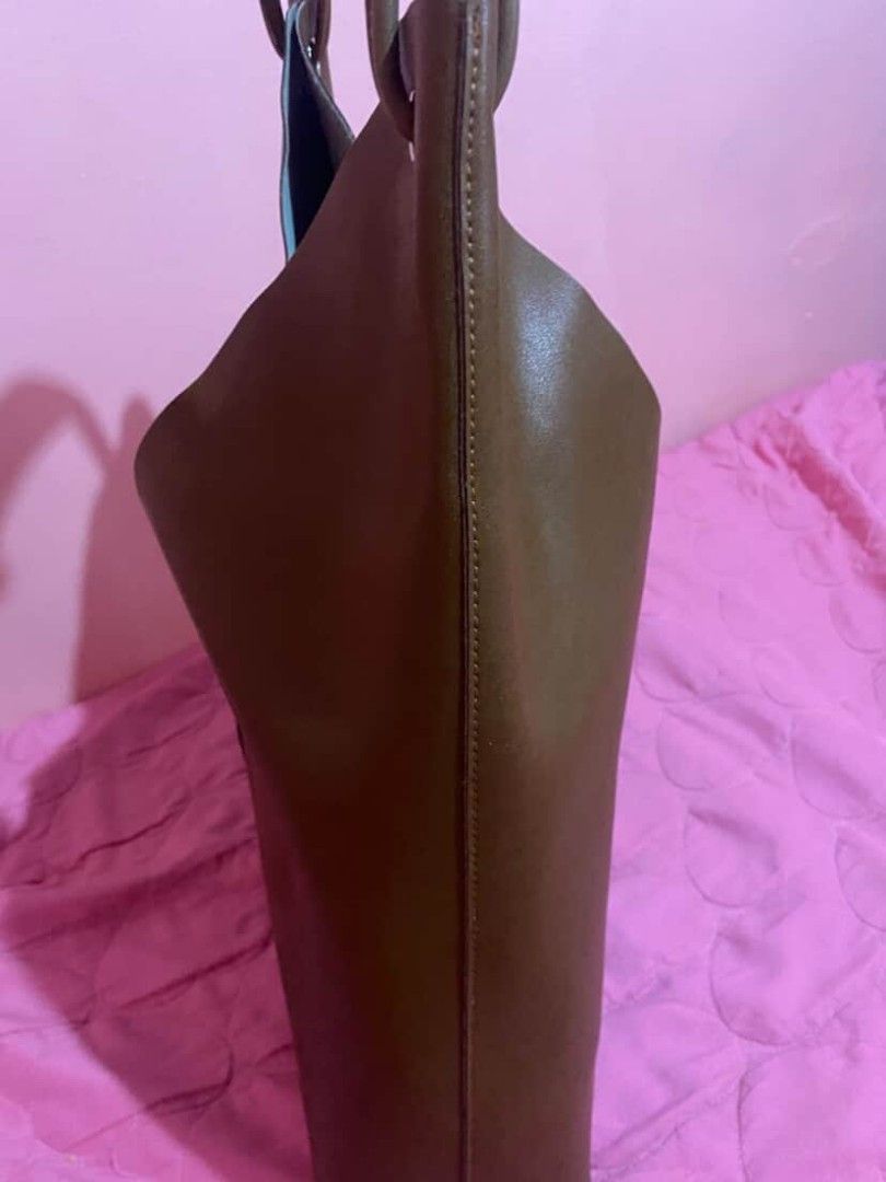 Pazzion Brown V-Cut Tote Bag (Category: Tote Bags) located in Manila. Submitted by goodbuying_items0211 (Listing ID 1466124716, Image 3). Description: Brown tote bag from Pazzion. Unique V-cut front design with structured side gussets. Dual handles feature a comfortable cushioned top wrap with silver-tone hardware accents. Smooth finish Genuine leather material. Roomy interior for daily essentials, work, or casual outings. Clean stitching along t