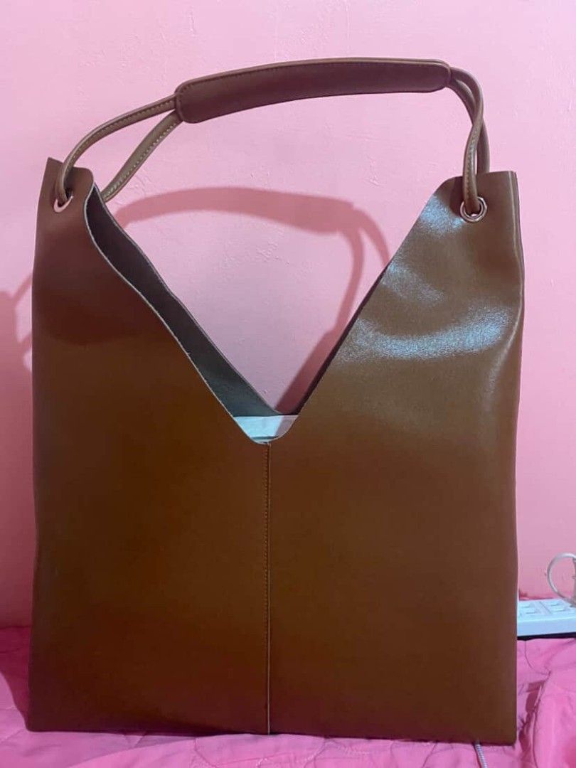 Pazzion Brown V-Cut Tote Bag (Category: Tote Bags) located in Manila. Submitted by goodbuying_items0211 (Listing ID 1466124716, Image 2). Description: Brown tote bag from Pazzion. Unique V-cut front design with structured side gussets. Dual handles feature a comfortable cushioned top wrap with silver-tone hardware accents. Smooth finish Genuine leather material. Roomy interior for daily essentials, work, or casual outings. Clean stitching along t