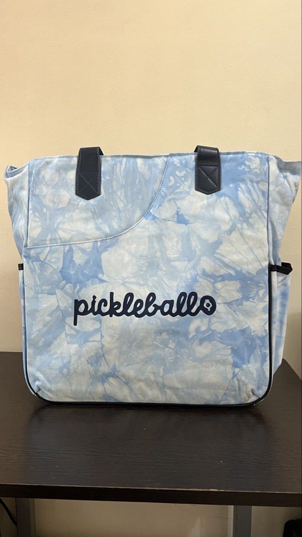 Pickleballer Blue Tie Dye Tote Bag (Category: Tote Bags) located in Manila. Submitted by kendsg (Listing ID 1466139729, Image 1). Description: - Trendy light blue tie-dye pattern with dark blue lettering - Premium dark blue leather top handles - Large exterior front pocket with a curved opening - Convenient side pockets on both ends for extra storage - Spacious interior designed for pickleball essentials.