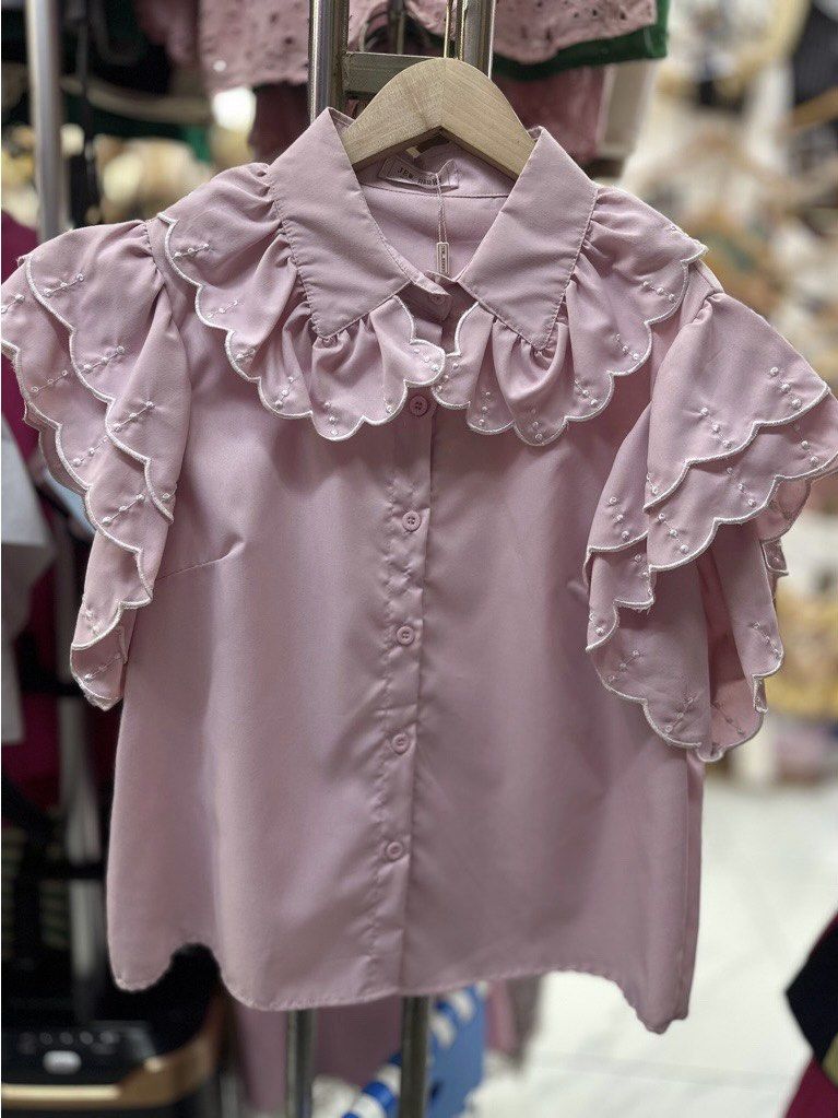 Pink Ruffle Collar Short Sleeve Blouse (Category: Blouses) located in Paranaque City. Submitted by jujudeclutterss (Listing ID 1466149120, Image 1). Description: - Condition: Brand new with original tag attached - Color: Dusty pink - Details: Large layered ruffle collar and multi-layered tiered ruffle sleeves - Accents: Scalloped white embroidery along the collar and sleeve hems - Closure: Front button-down with matching pink buttons - Fabric: Li