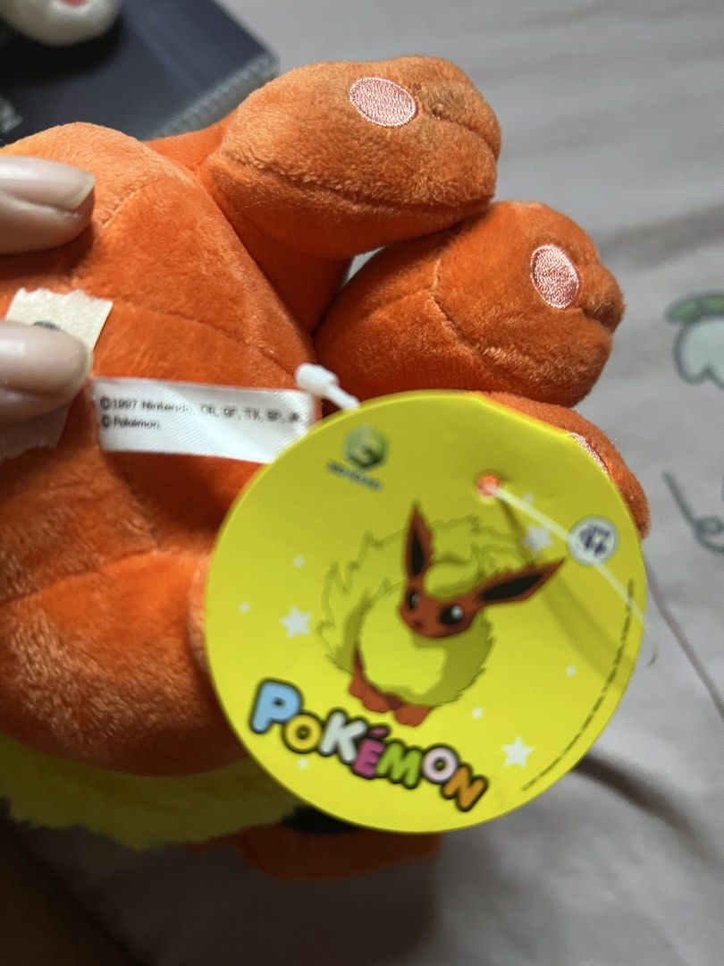 Pokemon Flareon Plush Toy (Category: Plushies & Soft Toys) located in Bulacan. Submitted by haven_plushie_dolls.888 (Listing ID 1466080296, Image 3). Description: - Official Pokémon Flareon plush toy - Soft orange fabric with vibrant yellow fluff on neck and tail - Large pointy ears with dark inner details - Sits upright independently - Includes original yellow hang tag and white tush tag - Clean and well-maintained collector's item.