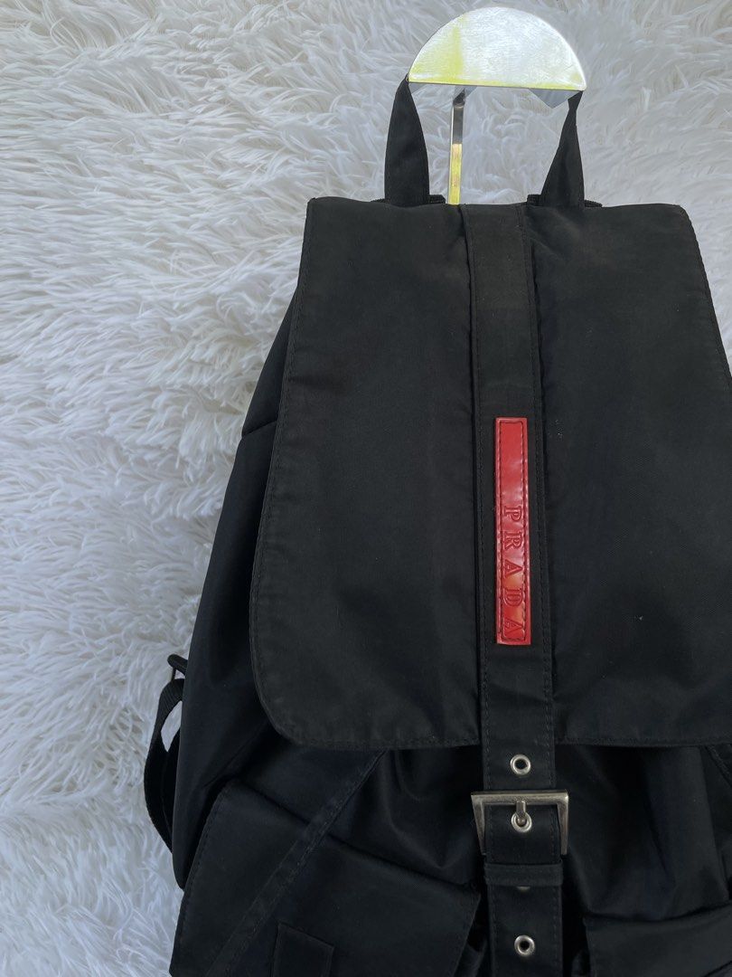 Prada Black Nylon Backpack (Category: Backpacks) located in San Carlos. Submitted by jessamaep_deer (Listing ID 1465970669, Image 2). Description: - Authentic Prada classic black nylon backpack - Sleek silver-tone hardware accents - Secure drawstring closure with buckled top flap - Two convenient front utility pockets with buckle straps - Spacious interior featuring a signature logo plaque and jacquard fabric lining - Adjustable shoulder straps a