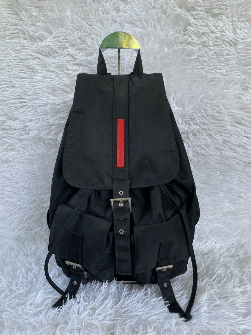 Prada Black Nylon Backpack (Category: Backpacks) located in San Carlos. Submitted by jessamaep_deer (Listing ID 1465970669, Image 1). Description: - Authentic Prada classic black nylon backpack - Sleek silver-tone hardware accents - Secure drawstring closure with buckled top flap - Two convenient front utility pockets with buckle straps - Spacious interior featuring a signature logo plaque and jacquard fabric lining - Adjustable shoulder straps a