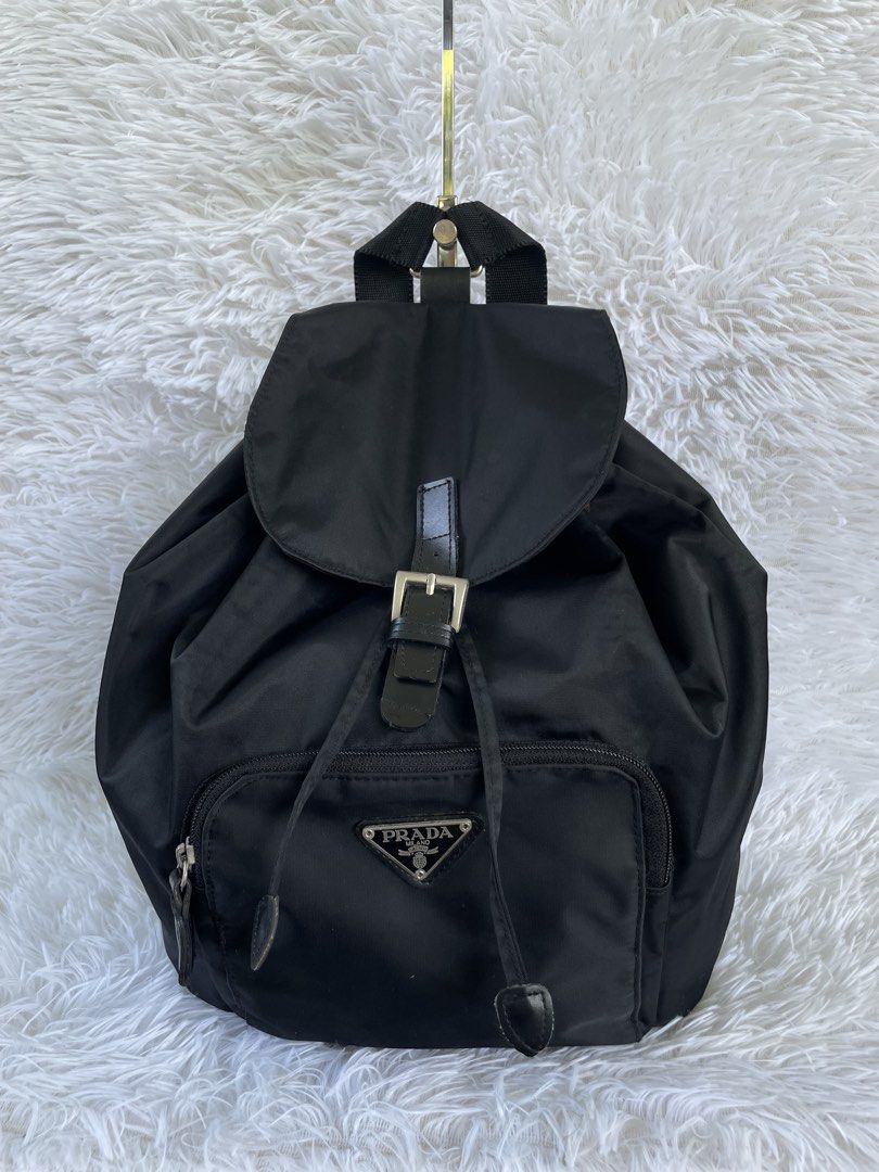 Prada Black Nylon Backpack (Category: Backpacks) located in San Carlos. Submitted by jessamaep_deer (Listing ID 1465971087, Image 1). Description: - Authentic Prada classic black nylon backpack - Front flap with buckle closure and secure drawstring pull - Front zippered pocket featuring the iconic triangular enamel logo plate - Stylish silver-tone hardware and signature patterned interior lining - Lightweight, durable, and practical for everyday 