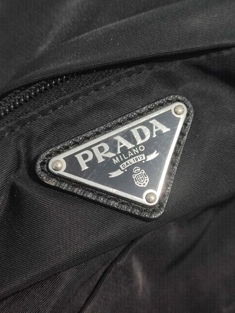 Prada Black Nylon Backpack (Category: Backpacks) located in Solana. Submitted by sonnymcamp28502 (Listing ID 1466099488, Image 2). Description: - Prada black nylon backpack with classic structured design - Features iconic metal triangle logo plate on the front zippered pocket - Equipped with premium silver hardware and smooth Lampo zippers - Includes top handle and comfortable adjustable shoulder straps - Interior features Prada Milano metal plaq