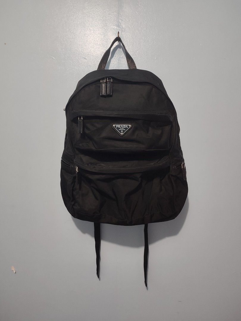 Prada Black Nylon Backpack (Category: Backpacks) located in Solana. Submitted by sonnymcamp28502 (Listing ID 1466099488, Image 1). Description: - Prada black nylon backpack with classic structured design - Features iconic metal triangle logo plate on the front zippered pocket - Equipped with premium silver hardware and smooth Lampo zippers - Includes top handle and comfortable adjustable shoulder straps - Interior features Prada Milano metal plaq