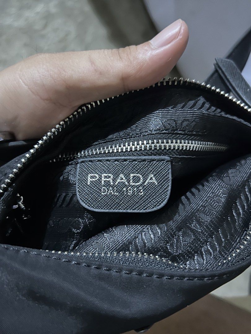 Prada Nylon Mini Shoulder Bag Black (Category: Luxury Bags & Wallets) located in Barotac Nuevo. Submitted by ehsherjohn27 (Listing ID 1466047678, Image 3). Description: - Authentic vintage Prada black nylon shoulder bag - Silver-tone hardware with iconic enamel triangle logo plaque - Signature jacquard fabric interior lining with a convenient zipper pocket - Single adjustable strap featuring a stylish buckle detail - Classic silhouette with plent