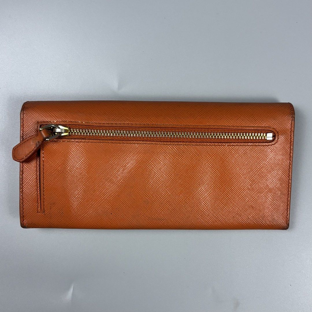 Prada Saffiano Leather Long Wallet Orange (Category: Wallets & Card holders) located in Mabalacat. Submitted by doughnutthrift (Listing ID 1466110022, Image 3). Description: - Prada long wallet crafted from vibrant orange Saffiano leather - Mixed gold and silver-tone hardware with iconic Prada lettering logo - Convenient zipped exterior coin compartment - Multiple interior card slots for easy organization - Made in Italy - Includes original authe