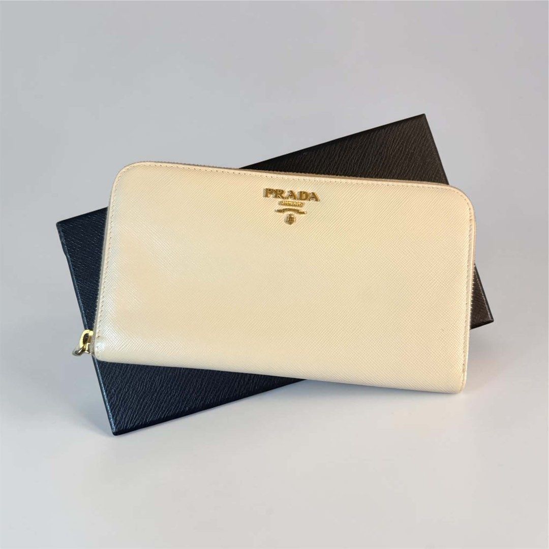 Prada Saffiano Leather Zip Around Wallet Beige (Category: Wallets & Card holders) located in Manila. Submitted by attypreciousyzncpa (Listing ID 1466149971, Image 1). Description: - Authentic Prada zip-around wallet in classic beige Saffiano leather - Elegant gold-toned hardware and iconic metal lettering logo on the front - Smooth zipper closure running along three sides for secure storage - Clean interior featuring organized compartments and mu