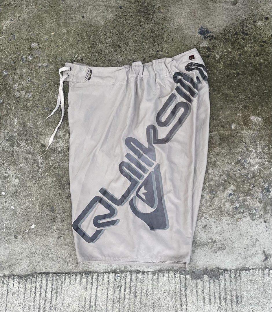 Quiksilver Board Shorts Beige Size 34 (Category: Swim Trunks & Board Shorts) located in Manila. Submitted by micoletszx81430 (Listing ID 1466083405, Image 1). Description: Waist: 30 to 34 - Brand: Quiksilver - Size: 34 - Color: Beige with large grey logo - Features: Drawstring closure with eyelets and a side cargo pocket on the right leg - Fit: Regular fit surf shorts - Condition: Clean and well-maintained overall.