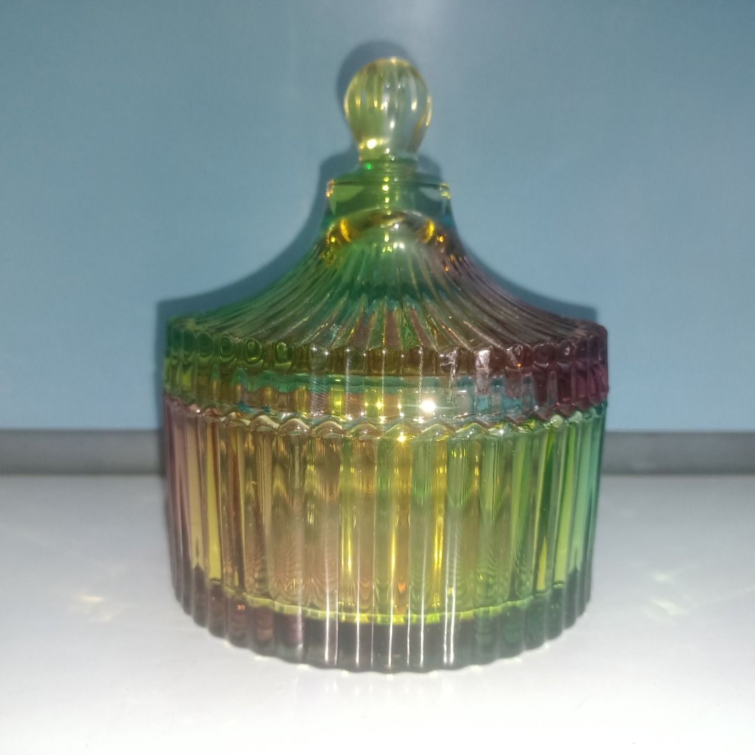 Rainbow glass candy jar with lid (Category: Food Organization & Storage) located in Munoz. Submitted by larryc1212 (Listing ID 1466113420, Image 3). Description: - Multi-colored ribbed glass jar with matching lid and round knob - Features a vibrant gradient of green, yellow, blue, and red hues - Textured vertical stripes on the translucent body and lid - Stands approximately 5 inches tall - Ideal for organizing jewelry, small trinkets, or storing