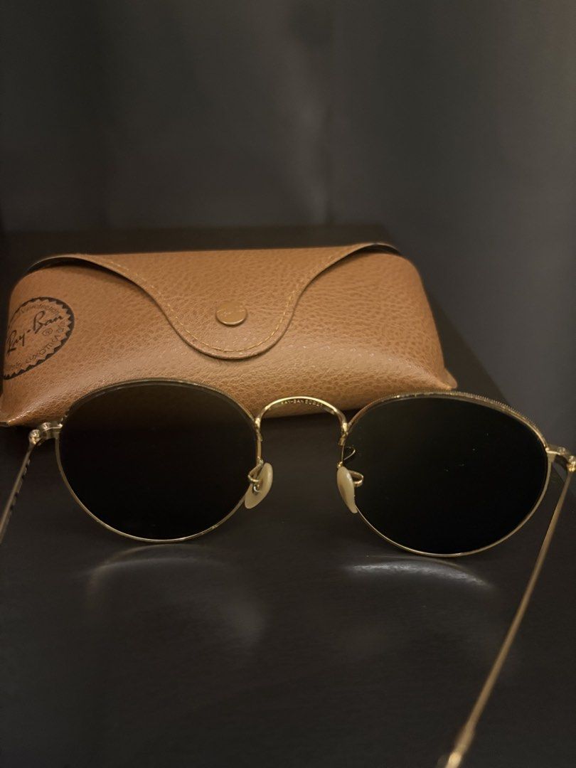 Ray-Ban Round Metal Sunglasses with Case (Category: Sunglasses & Eyewear) located in Paranaque City. Submitted by max_bully014 (Listing ID 1466091467, Image 3). Description: - Brand: Ray-Ban - Style: Classic round sunglasses with gold-tone frames - Lenses: Dark lenses in pristine condition, absolutely no scratches - Fit: Comfortable design that suits most face shapes - Inclusions: Original brown leatherette hard case with snap closure - Look: Tim