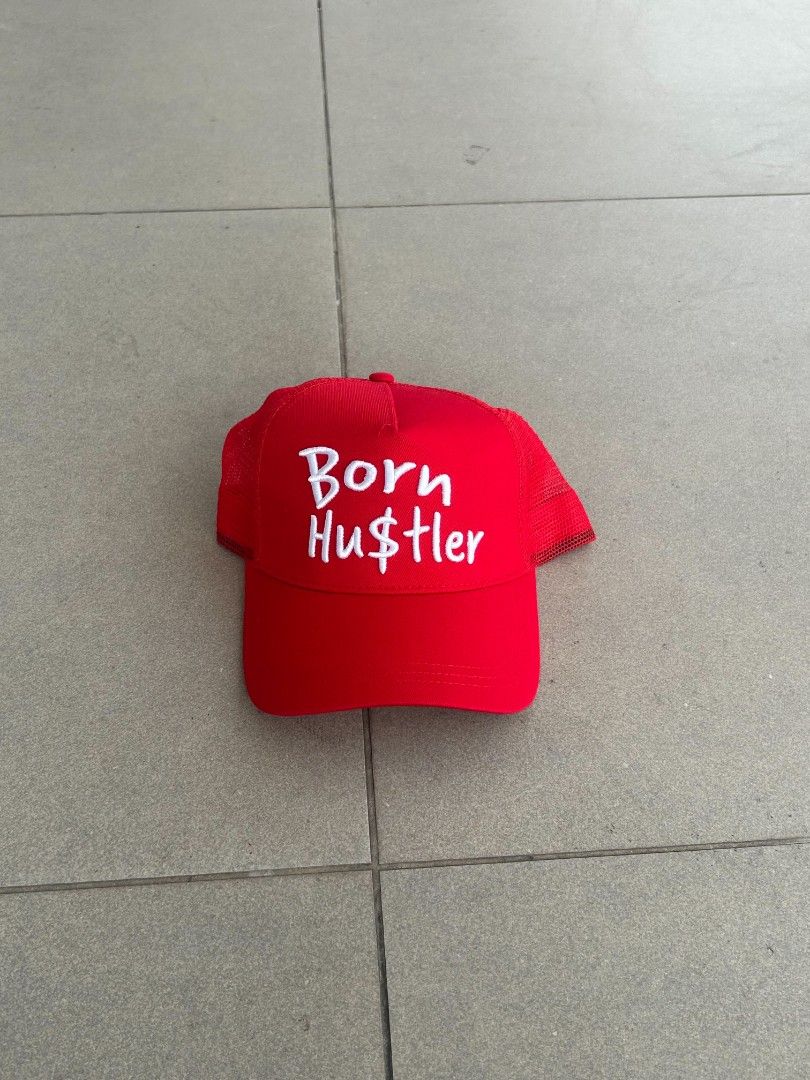 Red Born Hustler Trucker Hat (Category: Caps & Hats) located in Pasig City. Submitted by paulclzdo (Listing ID 1466072378, Image 1). Description: - Color: Vibrant red with white 'Born Hu$tler' embroidered text - Condition: Brand new, never worn - Features: Breathable mesh backing and clean interior lining - Closure: Adjustable snapback for a custom fit - Style: Ideal for casual streetwear and everyday wear.