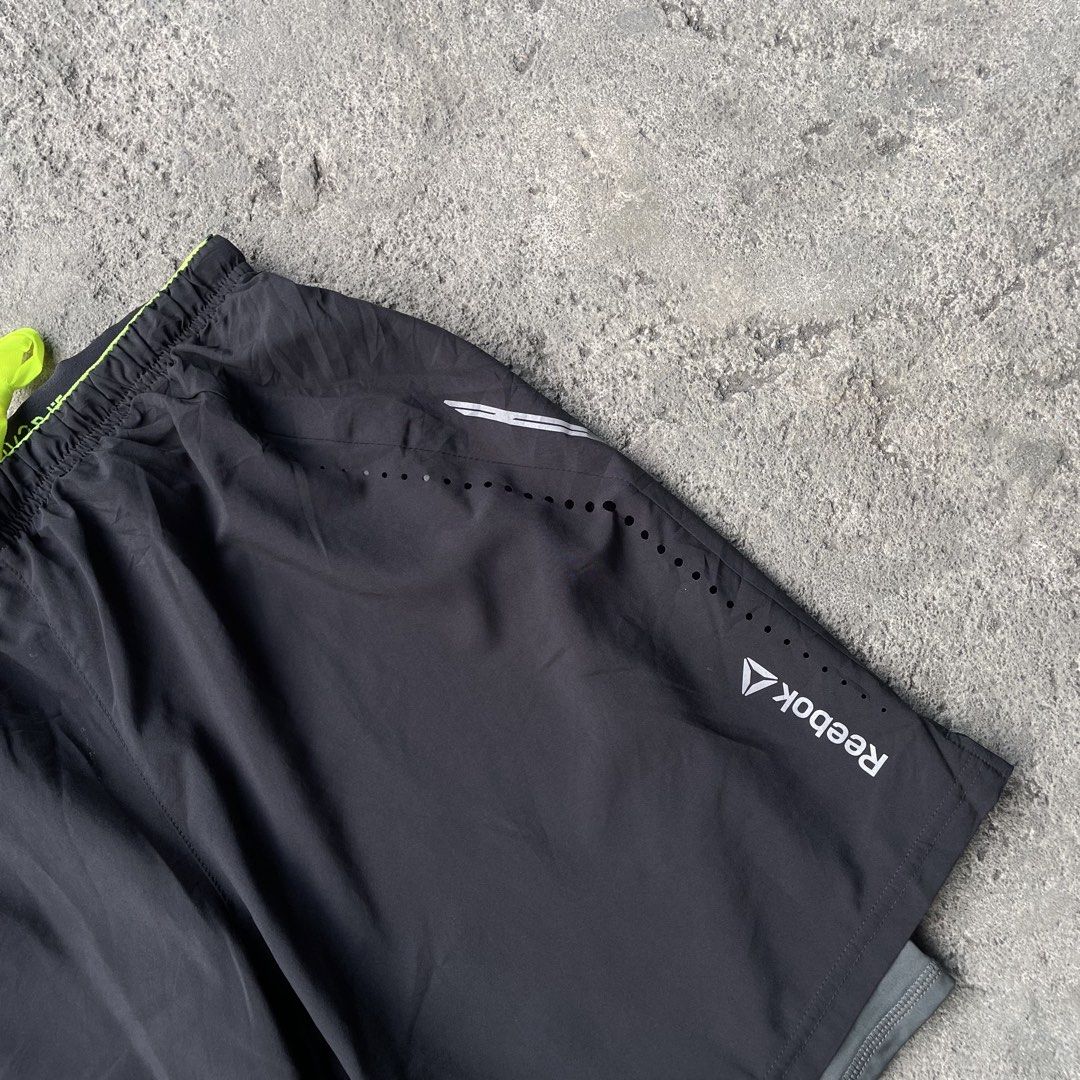 Reebok Black Running Shorts with Built-In Compression Liner (Category: Shorts) located in Polangui. Submitted by b0ssl00ts (Listing ID 1465962285, Image 3). Description: - Brand: Reebok - Color: Black with neon yellow drawstring and trim - Liner: Built-in grey compression liner for added support - Ventilation: Laser-cut side holes for maximum airflow - Details: Reflective silver accents and classic white Reebok logo on the left leg - Condition: B
