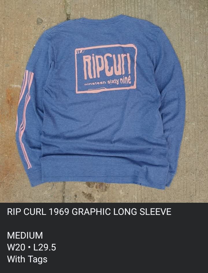 Rip Curl 1969 Graphic Long Sleeve Blue Medium (Category: Tshirts & Polo Shirts ) located in Cavite. Submitted by josephnl (Listing ID 1466130500, Image 2). Description: - Brand: Rip Curl - Style: Long sleeve shirt with standard fit - Color: Heather blue with pink accents - Design: Large pink graphic on back, smaller logo on front neck, and vertical pink stripes on sleeve - Size: Medium - Material: Cotton and polyester blend - Measurements: Width 