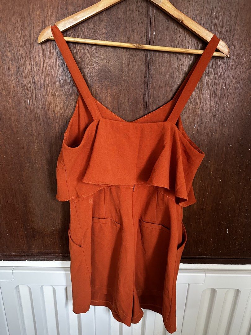 Rust Orange Layered Ruffle Romper Playsuit (Category: Rompers) located in Manila. Submitted by annika.rrl (Listing ID 1466017062, Image 3). Description: - Color: Rust orange - Style: Sleeveless romper with V-neckline and thick straps - Design: Layered ruffle overlay (front and back) with practical front pockets - Fit: Tailored shorts construction with a secure back zipper closure - Fabric: Lightweight and breathable, ideal for warm weather and ca