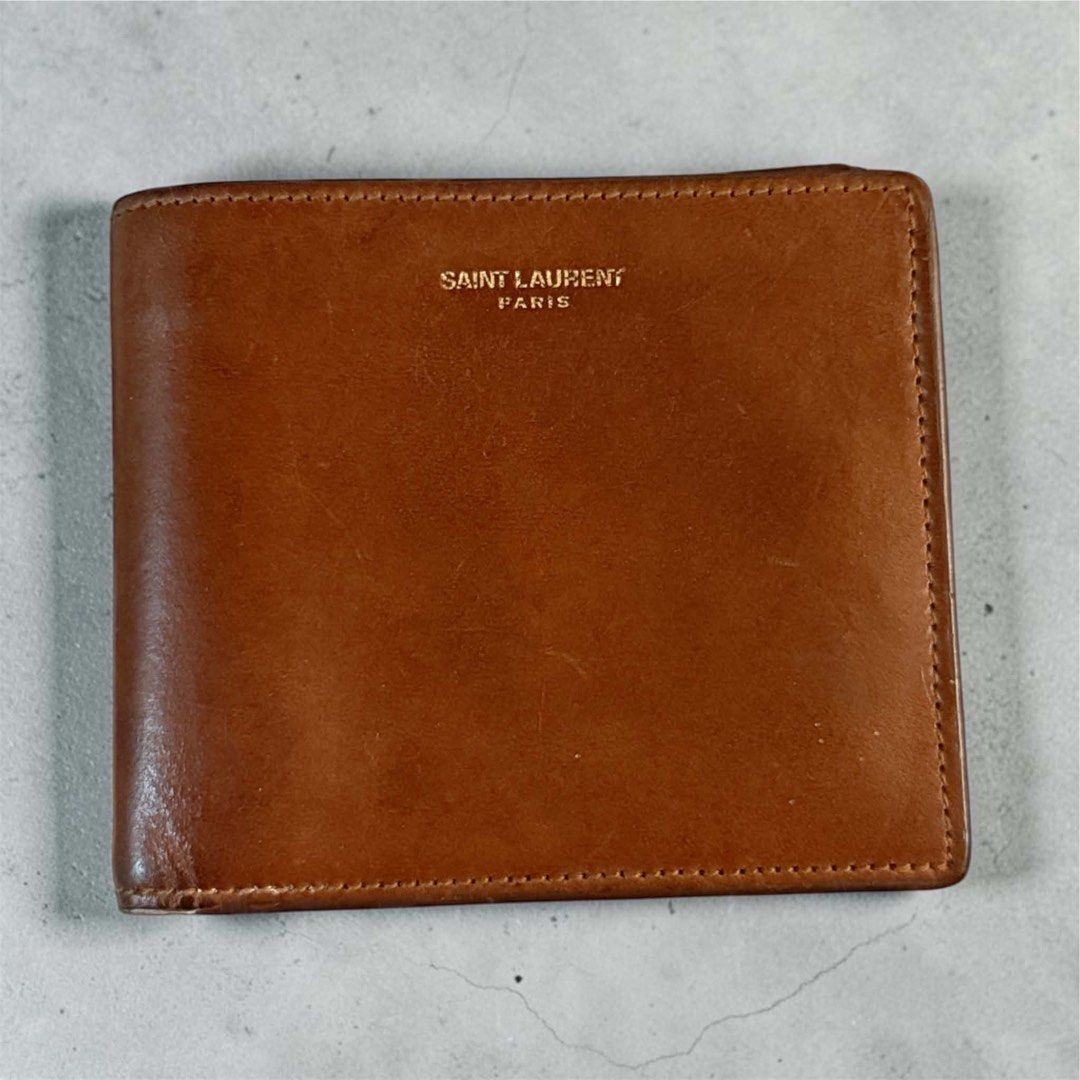 Saint Laurent Paris Brown Leather Bifold Wallet (Category: Wallets & Card holders) located in Manila. Submitted by attypreciousyzncpa (Listing ID 1466150185, Image 1). Description: - Authentic Saint Laurent Paris bifold wallet - Crafted from rich brown leather with a natural patina from regular use - Iconic gold-foil logo stamped on the front - Pocket-friendly, classic everyday size - Clean and durable stitching along all edges.