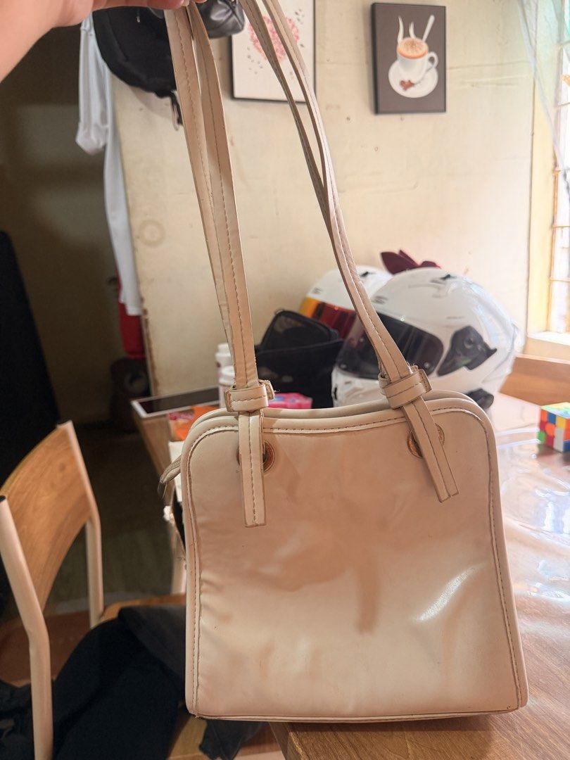 Shantel & Katie cream shoulder bag (Category: Shoulder Bags) located in Oas. Submitted by joice_29 (Listing ID 1465975654, Image 3). Description: - Brand: Shantel & Katie - Color/Design: Cream with brown quilted pattern trim - Shape: Structured square shoulder bag - Details: Front slip pocket with gold logo stamp, dual shoulder straps with hardware - Capacity: Practical size for daily essentials, phone, and wallet - Condition/Usage: Good everyday