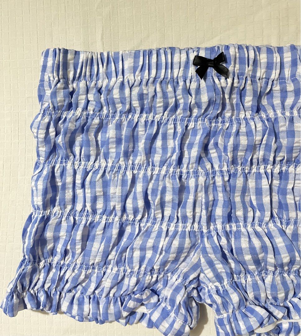 SHEIN Blue Gingham Ruffle Smocked Shorts Size S (Category: Shorts) located in Quezon City. Submitted by getitrightaway.ph (Listing ID 1466069317, Image 3). Description: - Brand: SHEIN - Size: Small (Fits EU 36 / US 4) - Design: Blue and white gingham print with a cute front bow and ruffle hems - Comfort: All-over smocked stretchy elastic material - Material: 100% polyester, machine washable - Condition/Use: Great for lounging or casual wear.