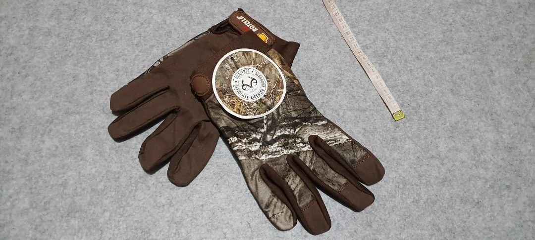Shell Rotella Realtree Camo Work Gloves (Category: Gloves) located in San Ildefonso. Submitted by rigor32eva20161 (Listing ID 1465977453, Image 1). Description: - Brand new with tags still attached - Official Realtree camo pattern - Durable build ideal for outdoor tasks, hunting, or garage work - Brown fabric design with a secure adjustable wrist strap - Features distinct rubberized Shell Rotella branding.