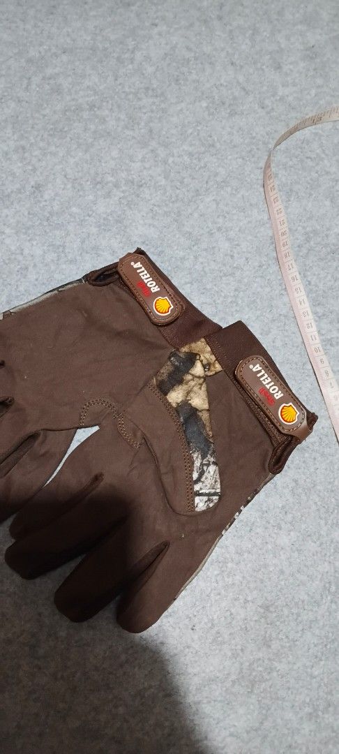 Shell Rotella Realtree Camo Work Gloves (Category: Gloves) located in San Ildefonso. Submitted by rigor32eva20161 (Listing ID 1465977453, Image 3). Description: - Brand new with tags still attached - Official Realtree camo pattern - Durable build ideal for outdoor tasks, hunting, or garage work - Brown fabric design with a secure adjustable wrist strap - Features distinct rubberized Shell Rotella branding.