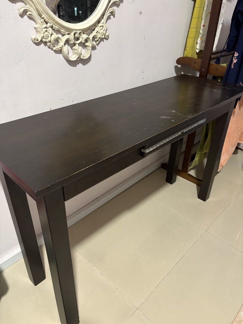 Solid wood table (Category: Tables & Sets) located in Subang Jaya. Submitted by nellissairina (Listing ID 1466029413, Image 1). Description: - Dark brown wooden desk with a simple, versatile design - Can be used as a study table or a narrow console table - Features a slim pull-out drawer with a patterned handle - Sturdy block legs ensuring stability - Condition: Rectangular surface has some scratches and scuffs from daily use - Self-collection on