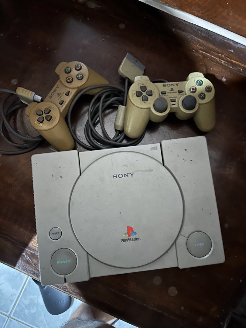 Sony PlayStation 1 Console with Two Controllers (Category: PlayStation) located in Tarlac. Submitted by thrifttuff_ (Listing ID 1466063909, Image 1). Description: - Authentic original Sony PlayStation console - Includes 2 original wired controllers with intact plugs and cables - Classic grey chassis with vintage yellowing and surface marks from age - Power button and disc lid mechanism tested and working - Ideal restoration project for retro game