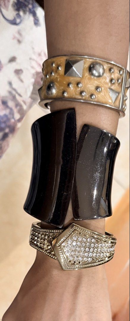 Statement cuffs bangle (Category: Bracelets) located in Kuala Lumpur. Submitted by aks77 (Listing ID 1466097838, Image 1). Description: Prices listed top to wrist : - RM 35 : Textured beige enamel with metallic studs and pyramid accents - RM 38 : Wide curved black glossy cuff (some signs of wear) - RM 48 : Shiny gold-tone metal with clear rhinestones and geometric front Versatile styling: Wear stacked together or separately! High quality solid me