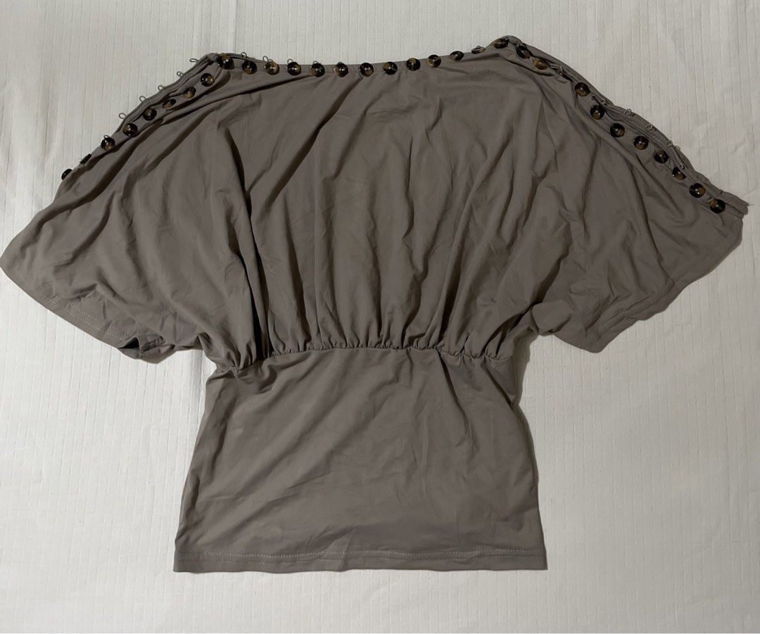 Taupe Cold Shoulder Button Detail Top Size M (Category: Blouses) located in Quezon City. Submitted by getitrightaway.ph (Listing ID 1466063361, Image 2). Description: - Color: Taupe Grey - Size: M (Made in China) - Design: Cold shoulder cutouts with chic tortoiseshell buttons - Fit: Fitted waist with gentle gathering and short dolman sleeves - Versatility: Neutral tone, super easy to pair with shorts or denim - Condition: Excellent/unworn (flat l