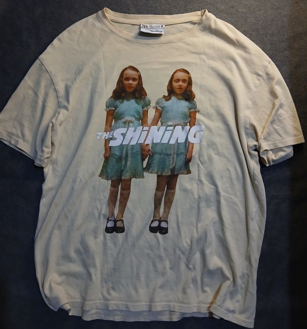 The Shining Graphic HORROR TEE (Category: Tshirts & Polo Shirts ) located in Caloocan City. Submitted by benthriftshp (Listing ID 1466120727, Image 1). Description: - Brand: Zara - Design: The Shining twins graphic print (front and back) - Color: Cream - Size: Medium (tag at collar) - Material: 100% Cotton, relaxed fit - Measurements: ~21" pit-to-pit, ~27" length - Flaw: Small pinhole near the right shoulder seam 850+sf.