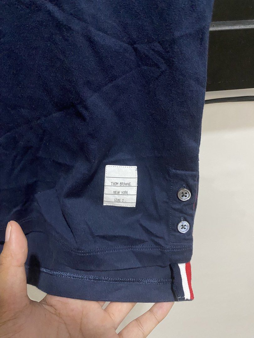 Thom Browne Navy Pocket Tee Size 2 (Category: Shirts) located in Manila. Submitted by hell_market (Listing ID 1466119183, Image 3). Description: - Brand: Thom Browne New York - Color: Navy Blue - Material: 100% Cotton (Made in Italy) - Size: 2 (Medium) - Single chest pocket with iconic tricolor stripe detail - Side vents featuring button closures and signature grosgrain ribbon trim - Classic woven name tag near the hem - Condition: Excellent pre-