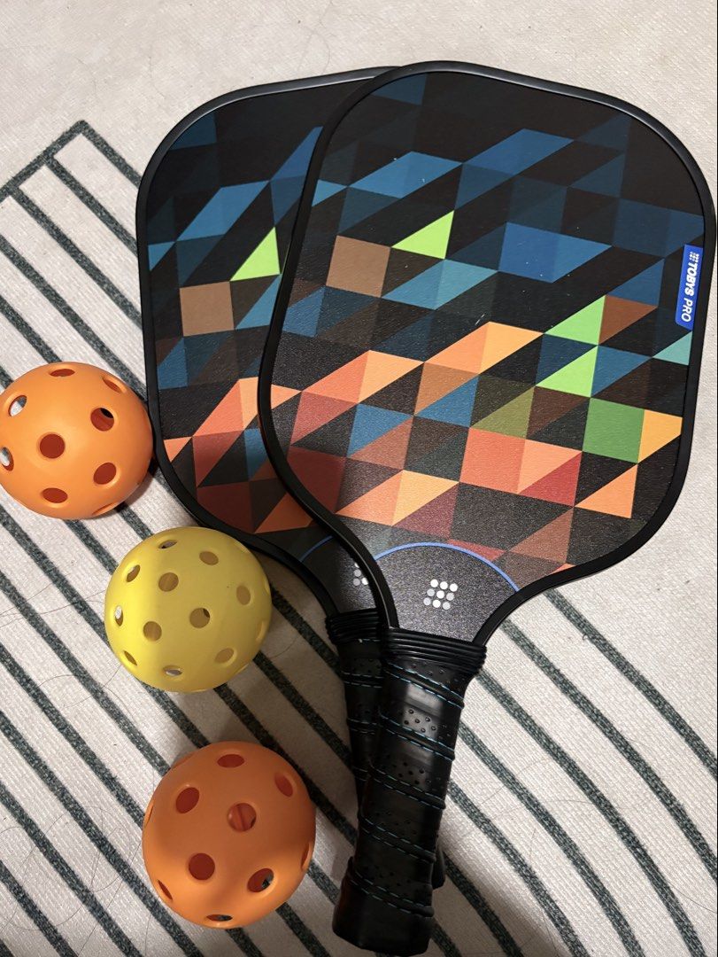 Tobys Pro Fiber Pro 1000 Pickleball Set (Category: Racket and Ball Sports) located in Plaridel. Submitted by thefatbearinside (Listing ID 1466042183, Image 3). Description: - Brand/Model: Tobys Pro Fiber Pro 1000 Pickleball Set - Paddle Weight: Ultra-lightweight at 206g each for effortless swings - Material: Durable fiberglass face with USAPA standard pickleballs - Design: Eye-catching geometric pattern in blue, orange, black, and green - Complet
