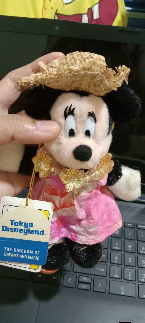 Tokyo Disneyland Minnie Mouse (Category: Plushies & Soft Toys) located in Gapan. Submitted by montesnora80204 (Listing ID 1466095847, Image 2). Description: - Authentic Tokyo Disneyland merchandise with original tag attached - Features Minnie Mouse in a pink tropical floral dress, yellow flower lei, and mini straw hat - Hand-held, compact size perfect for display or collecting - Flawless condition: clean plush material with no stains or damage.