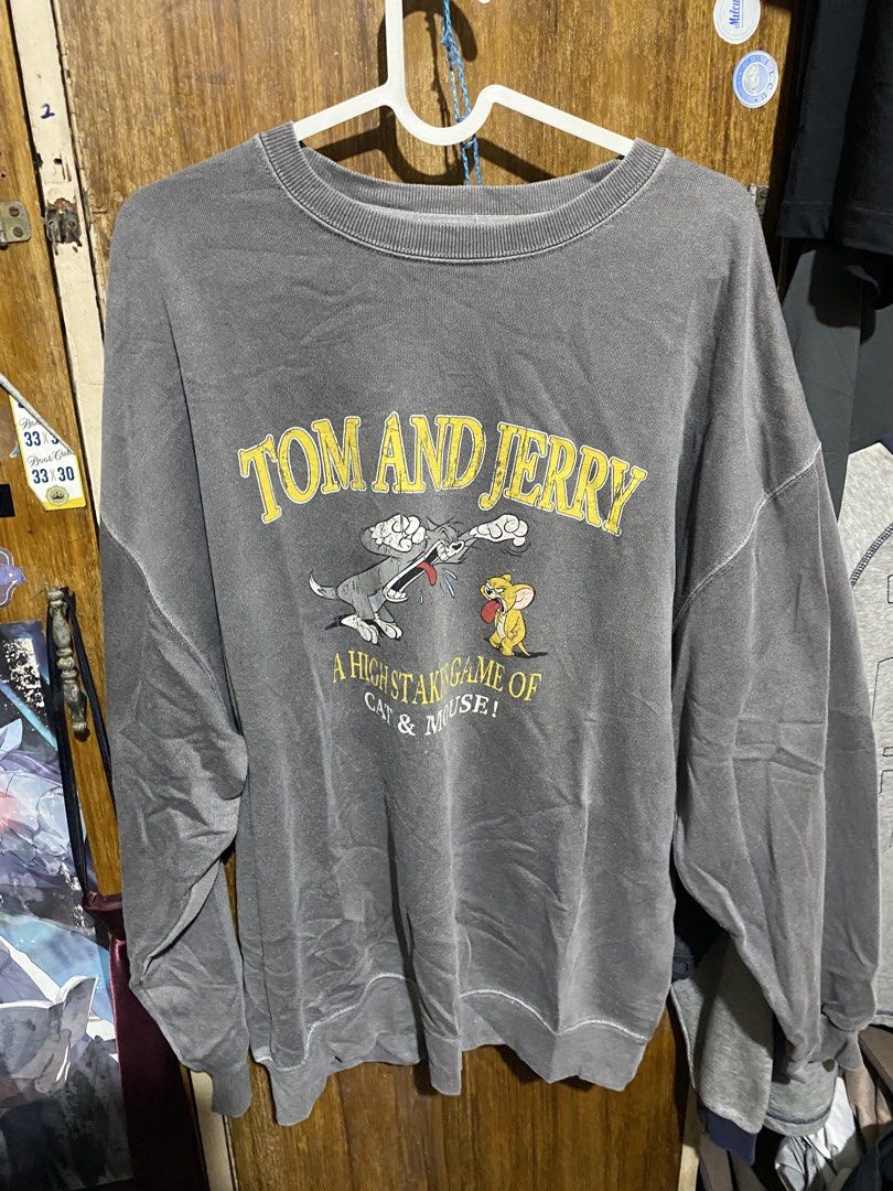 Tom and Jerry Graphic Sweatshirt Grey (Category: Coats, Jackets and Outerwear) located in Imus. Submitted by frootiloots4103 (Listing ID 1466036803, Image 1). Description: - Color: Washed grey - Design: Front graphic with 'A high staking game of cat & mouse!' text and small embroidered Tom & Jerry lettering on the upper back - 25x29 - Fit: Relaxed fit with dropped shoulders - Material: Heavyweight cotton fleece with ribbed collar, cuffs, and hem 