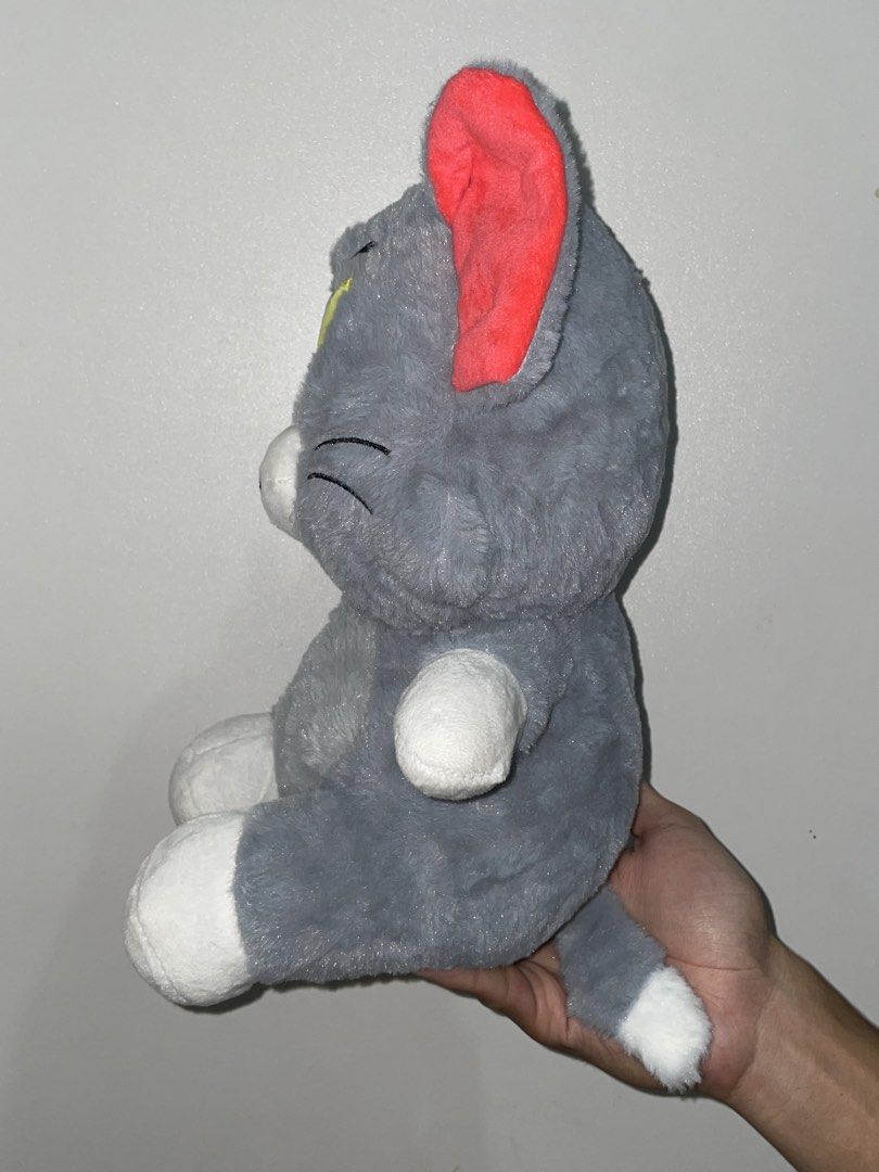 Tom and Jerry Tom Plush Toy (14 inch) (Category: Plushies & Soft Toys) located in Las Pinas. Submitted by picksbycie (Listing ID 1466041265, Image 2). Description: - Character: Tom (Tom and Jerry) - Material: Soft and cuddly plush texture - Design: Grey body with white paws, muzzle, tail tip, bright red inner ears, and yellow embroidered eyes - Features: Includes a hanging string at the top and a functional zipper down the back - Condition: Excel