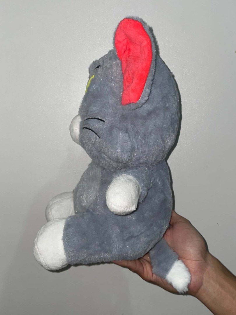 Tom plush toy stuffed animal (Category: Plushies & Soft Toys) located in Cavite. Submitted by rare_dye (Listing ID 1466104656, Image 2). Description: - Character: Tom Cat from Tom and Jerry - Color: Classic grey and white with bright red inner ears - Features: Embroidered yellow eyes, black whiskers, cute smile, white paws and tail tip - Extra Details: Zipper closure at the back of the head and hanging loop on top - Texture: Soft furry material a