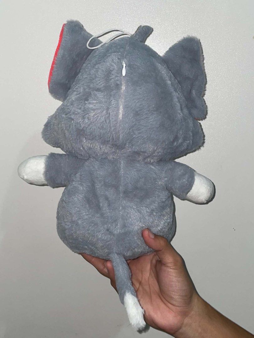 Tom plush toy stuffed animal (Category: Plushies & Soft Toys) located in Cavite. Submitted by rare_dye (Listing ID 1466104656, Image 3). Description: - Character: Tom Cat from Tom and Jerry - Color: Classic grey and white with bright red inner ears - Features: Embroidered yellow eyes, black whiskers, cute smile, white paws and tail tip - Extra Details: Zipper closure at the back of the head and hanging loop on top - Texture: Soft furry material a