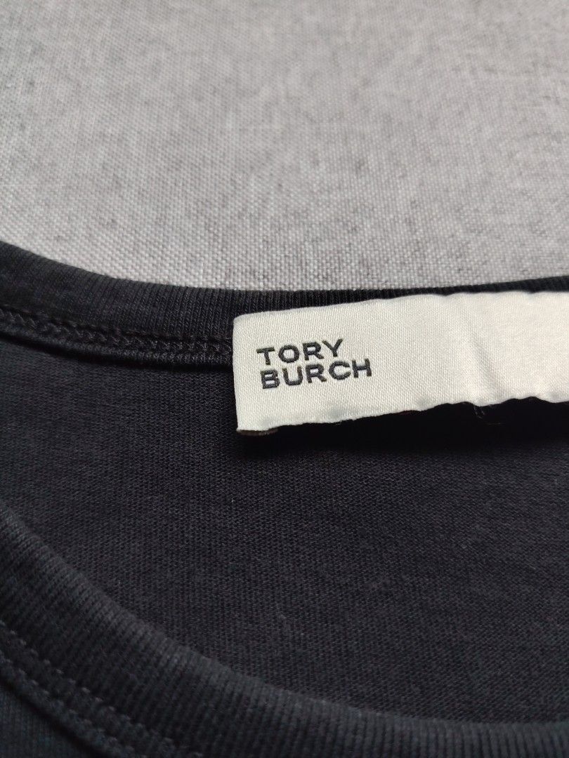 Tory Burch 'Double T' Logo Shirt (Category: Shirts) located in Taguig. Submitted by _theroom.ph (Listing ID 1465984591, Image 3). Description: - Brand: Tory Burch - Color: Black with large white graphic logo - Size: Medium (tag inside) - Material: Soft and breathable cotton - Design: Short sleeves, crew neck - Condition: Excellent for casual daily wear - Origin: Made in China Tory Burch 'Double T' Logo Shirt Size Medium 23 x 18 Excellent Conditio