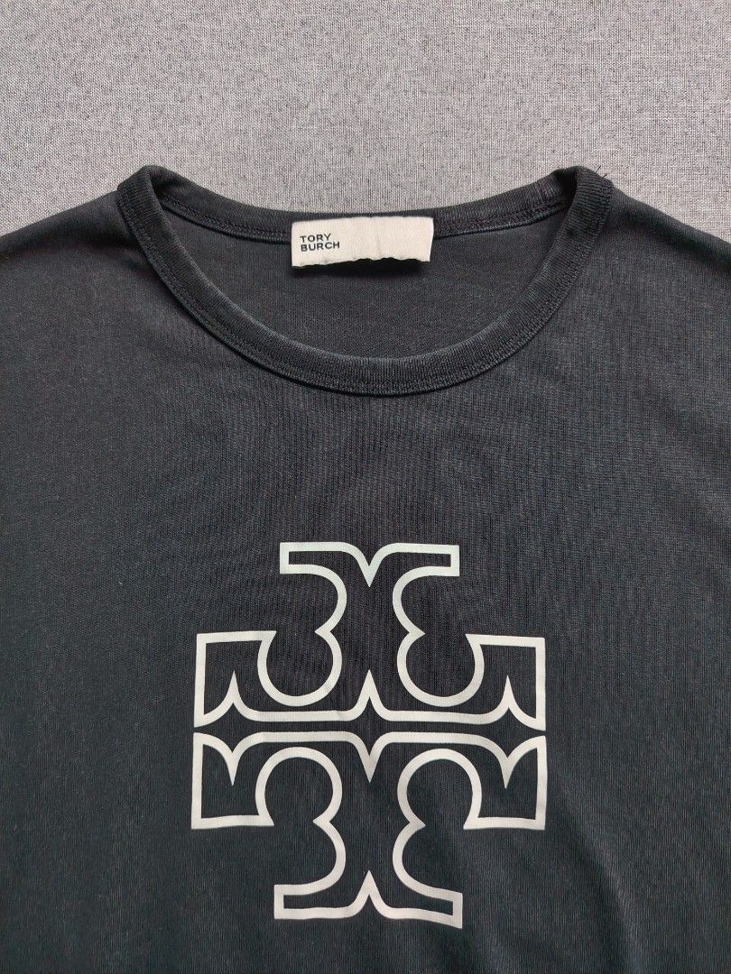 Tory Burch 'Double T' Logo Shirt (Category: Shirts) located in Taguig. Submitted by _theroom.ph (Listing ID 1465984591, Image 2). Description: - Brand: Tory Burch - Color: Black with large white graphic logo - Size: Medium (tag inside) - Material: Soft and breathable cotton - Design: Short sleeves, crew neck - Condition: Excellent for casual daily wear - Origin: Made in China Tory Burch 'Double T' Logo Shirt Size Medium 23 x 18 Excellent Conditio